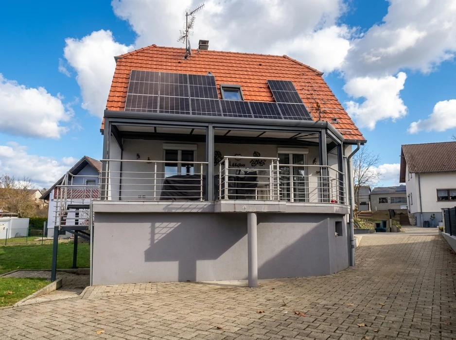 Maison individuelle avec toiture en tuiles terre cuite équipée de panneaux photovoltaïques monocristallins