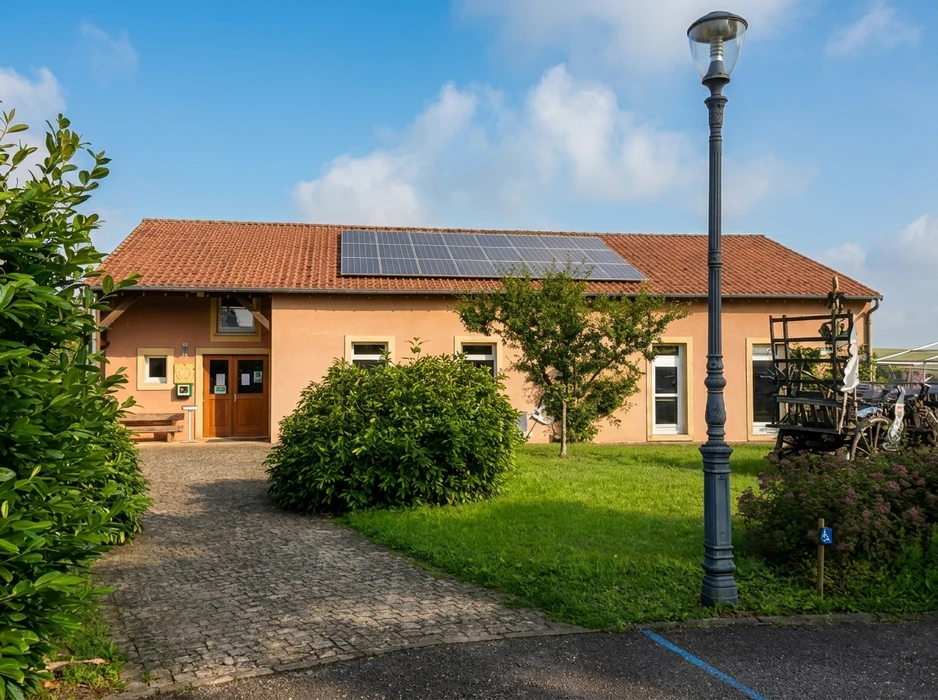 Bâtiment rural réhabilité, façade enduit ocre-rose, toiture en tuiles canal avec panneaux photovoltaïques monocristallins
