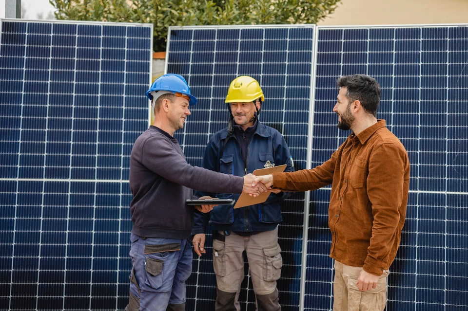 Ouvrier en équipement de protection individuelle avec casque jaune et harnais de sécurité travaillant sur installation de panneaux solaires photovoltaïques