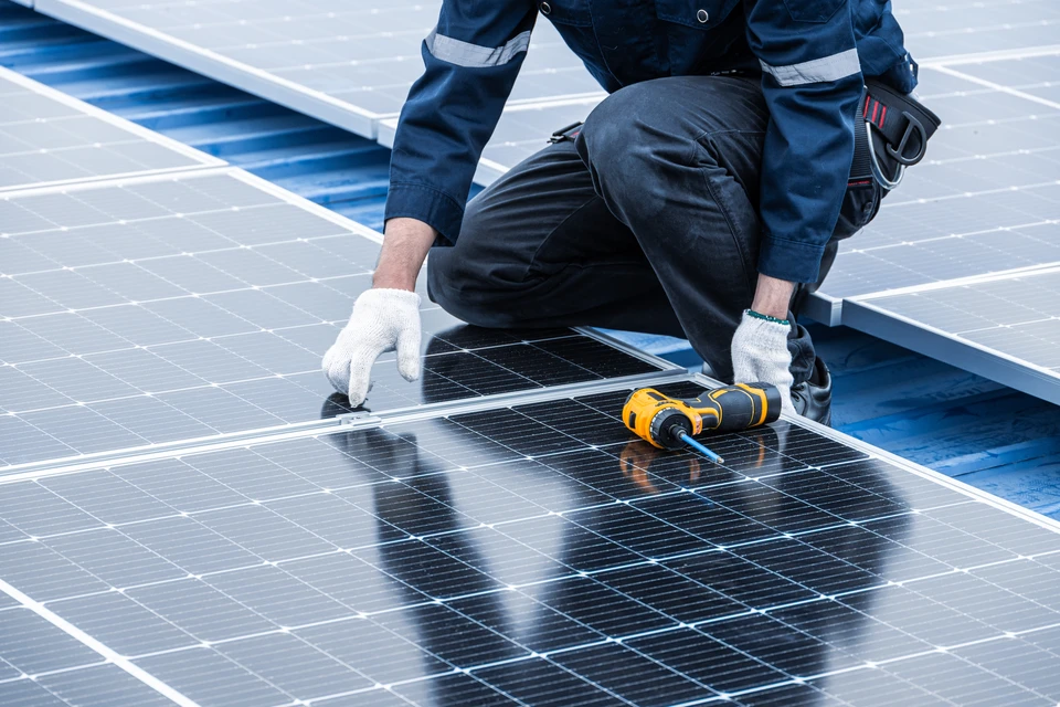 Deux ouvriers en équipement de sécurité installent des panneaux solaires photovoltaïques sur une toiture